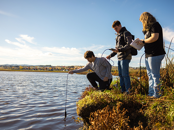 Students recording water data by taking samples