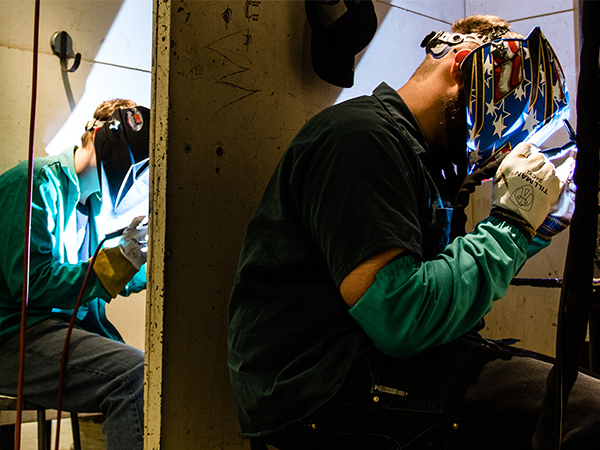 Two students welding unknown projects